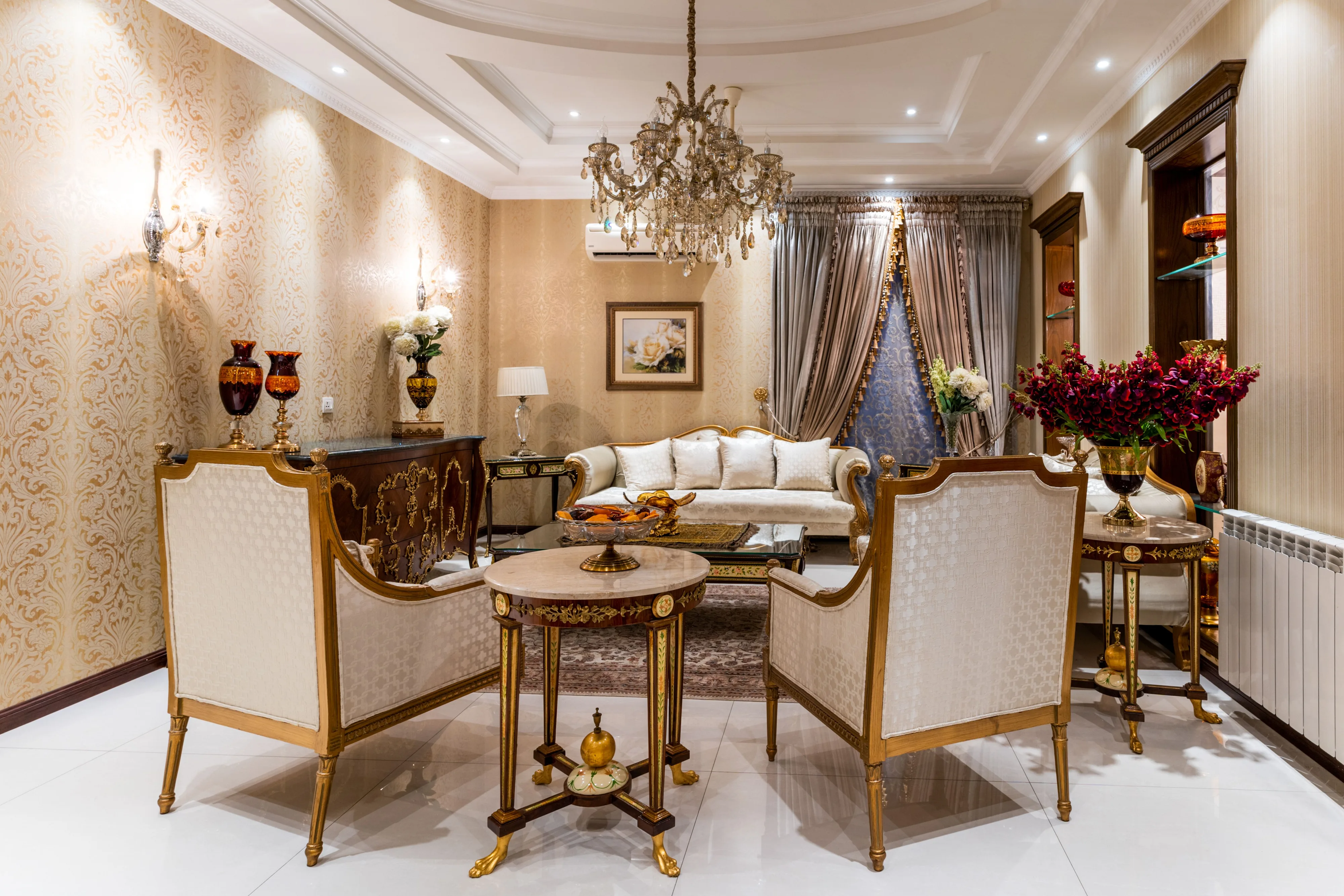 A refined living room with pale patterned wallpaper and warm gold accents
